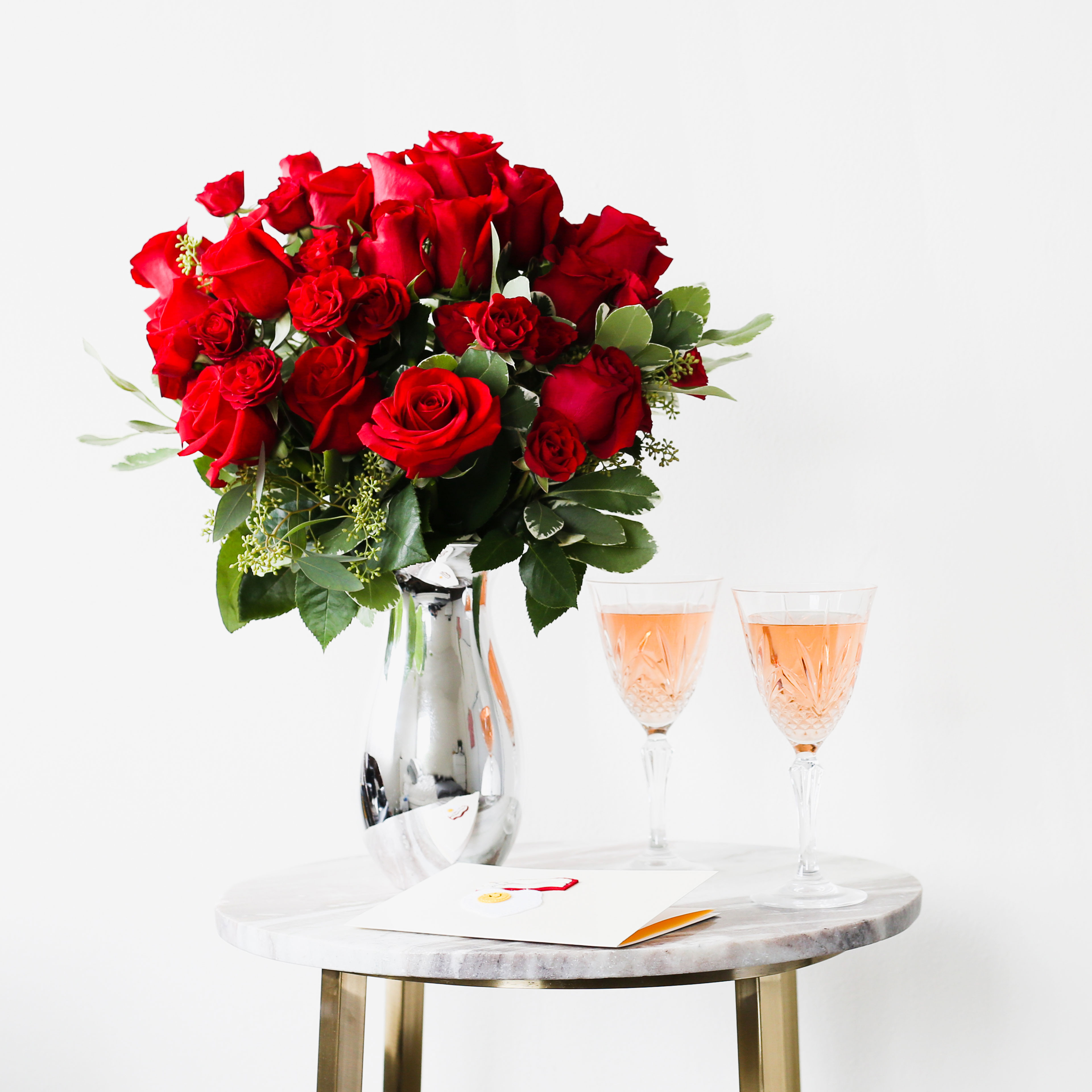 red roses in a vase on table with champagne