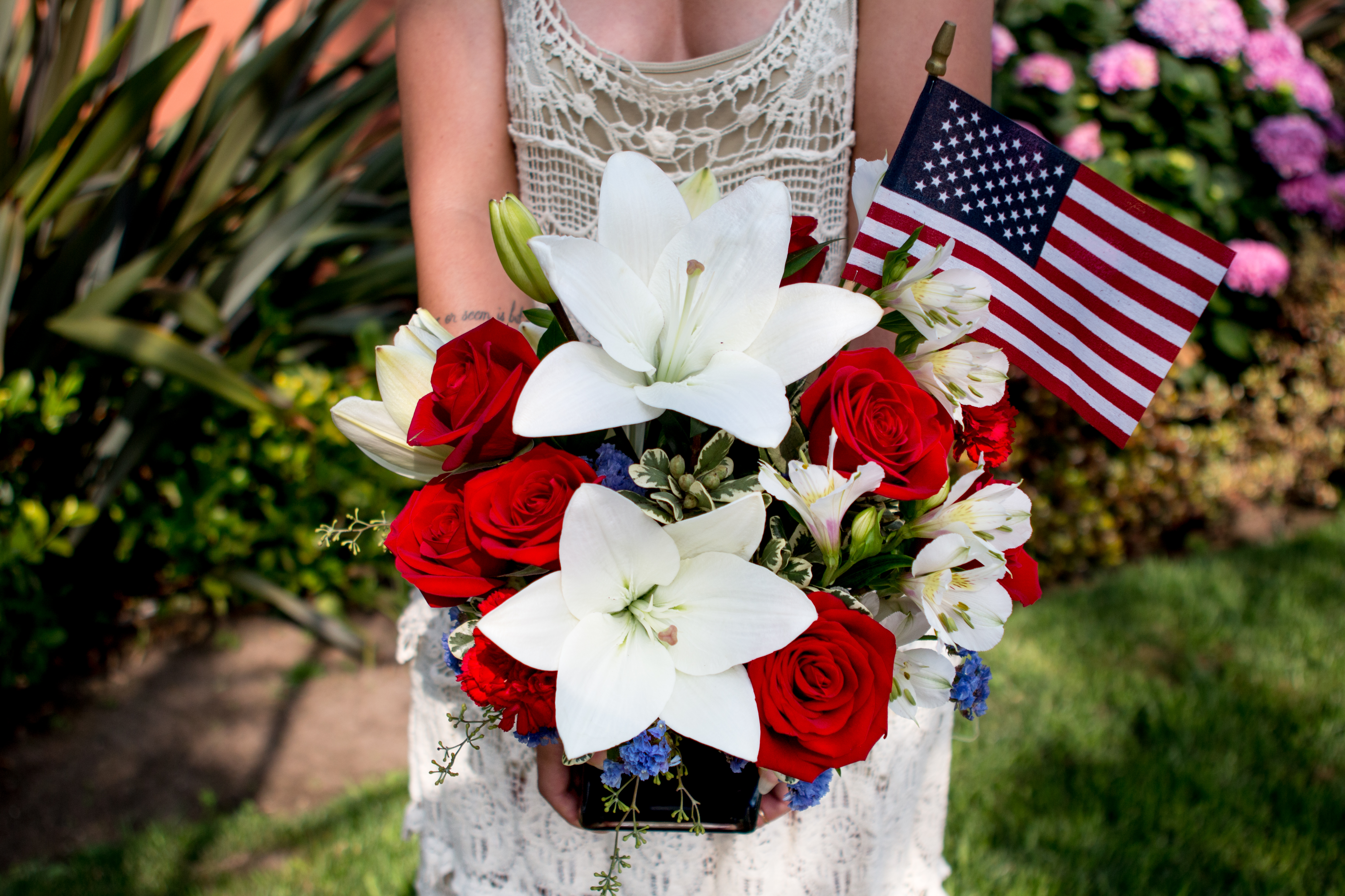 white lilies and red roses in a blue vase with American flag