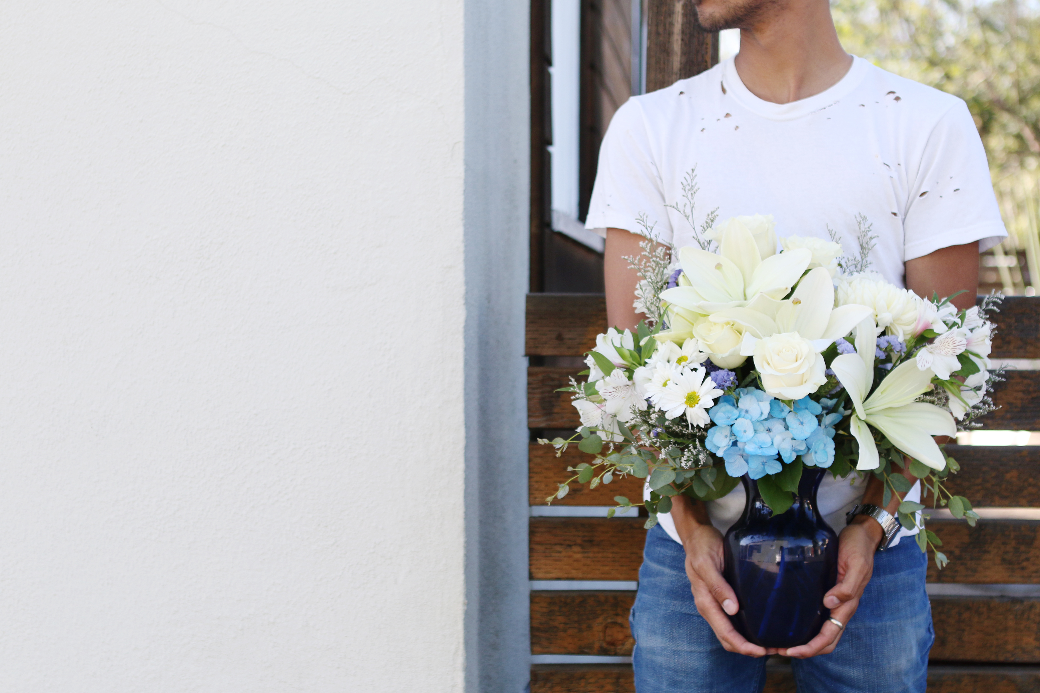 white lilies, blue hydrangea, and greenery in blue vase