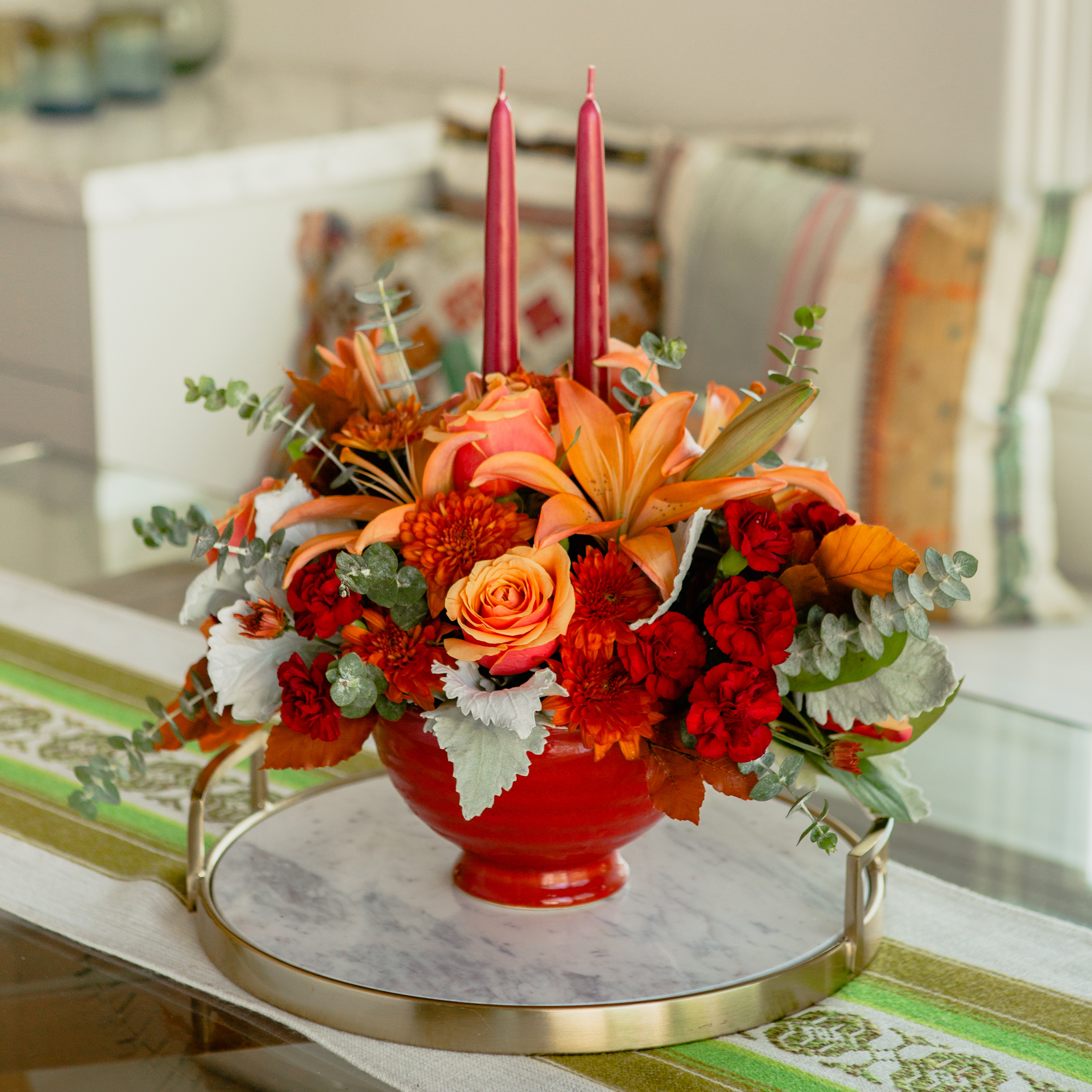 Orange lilies, orange roses, maroon carnations, and more fill an orange thanksgiving centerpiece
