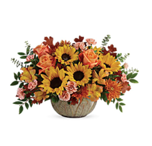 yellow sunflowers, peach carnations, bronze mums, and more fill a ceramic bowl