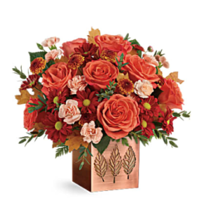 Orange roses, peach carnations, bronze mums, and more fill a copper cube vase