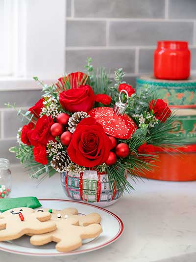 Red christmas flowers fill an ornament vase on a counter with cookies