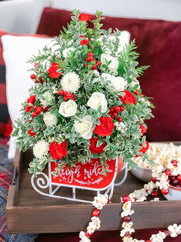 Red and white flower tree fill a vintage sleigh