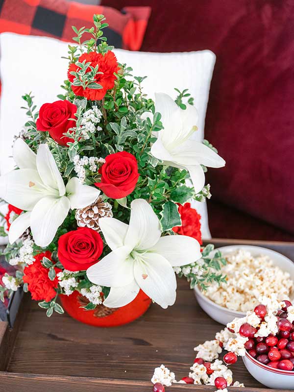 White lilies and red roses fill a red stoneware centerpiece