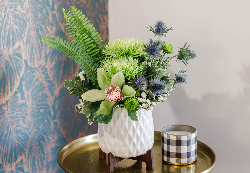 Orchid and greenery fill a beautiful white vase