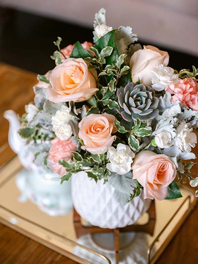 Peach roses and succulents fill a white vase